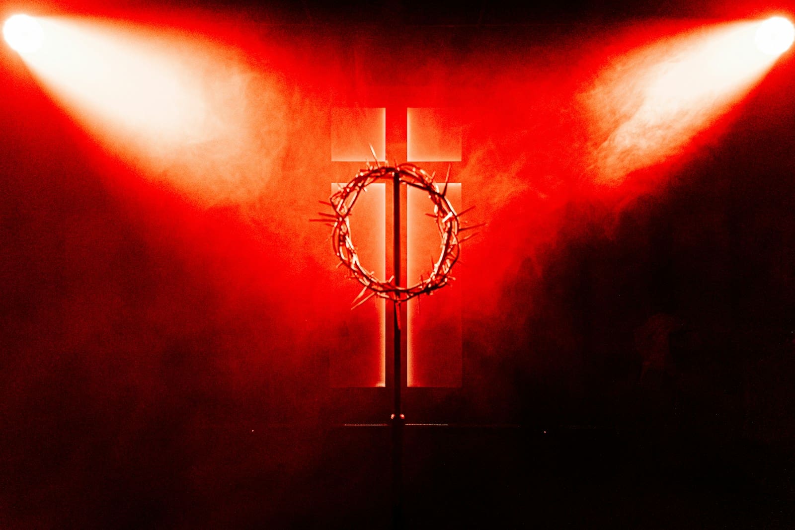 a red light shines on a cross with a crown of thorns on it
